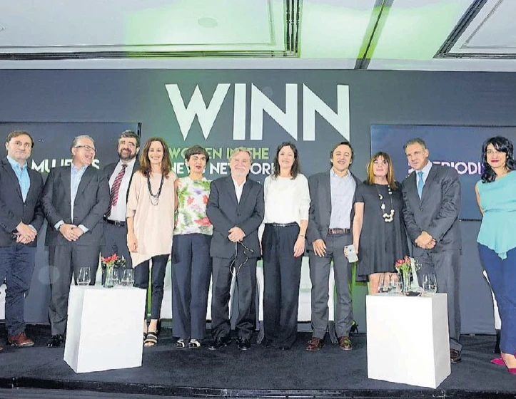 Participantes de un encuentro de WINN reunidos en el escenario, frente al nombre de la red